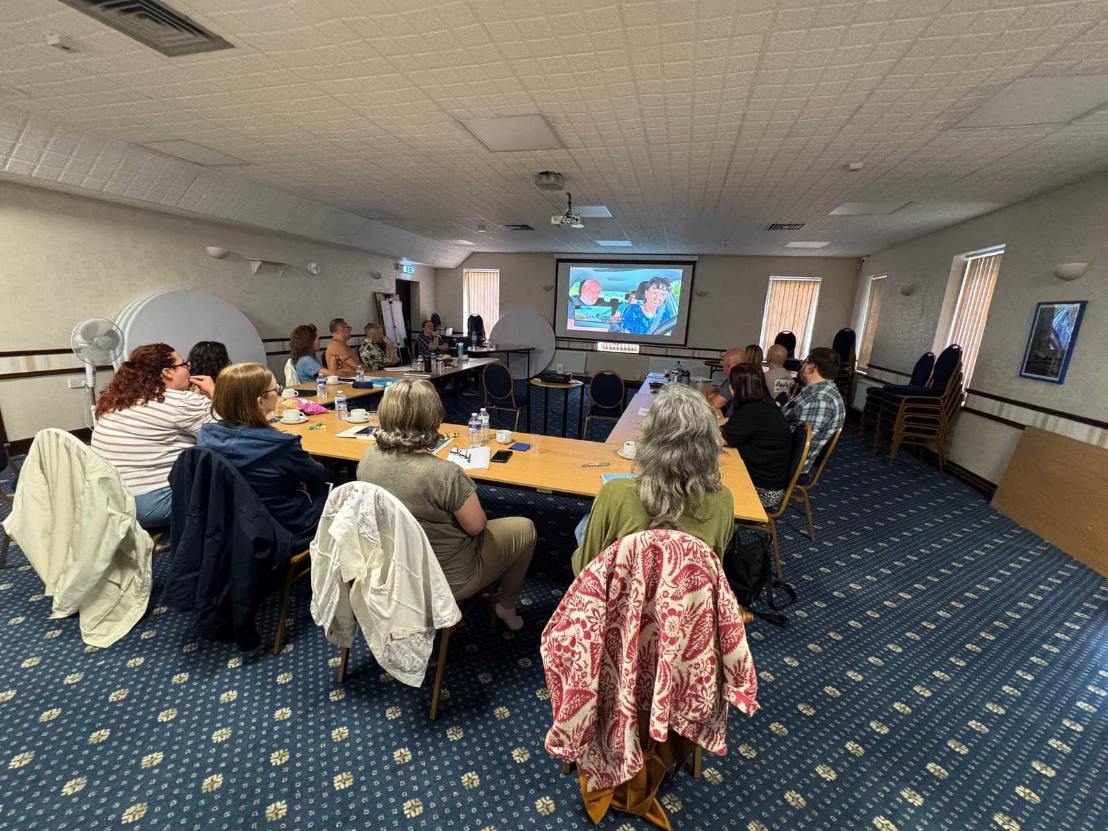 A workshop group reviewing an in-car lesson on screen